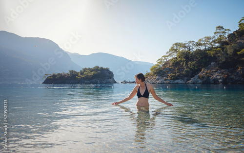 Summer lifestyle portrait of Happy traveller woman in black swimsuit enjoys her tropical beach vacation in Oludeniz Blue Lagoon Turkey. © YURII Seleznov