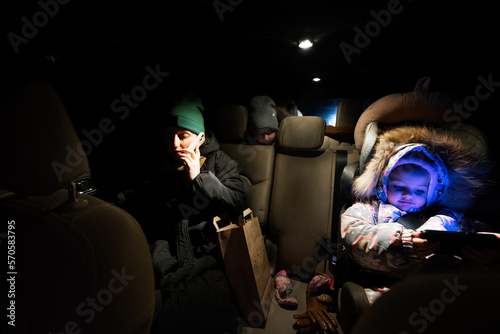 At the back seat of car mother with children look at phone in night driving.
