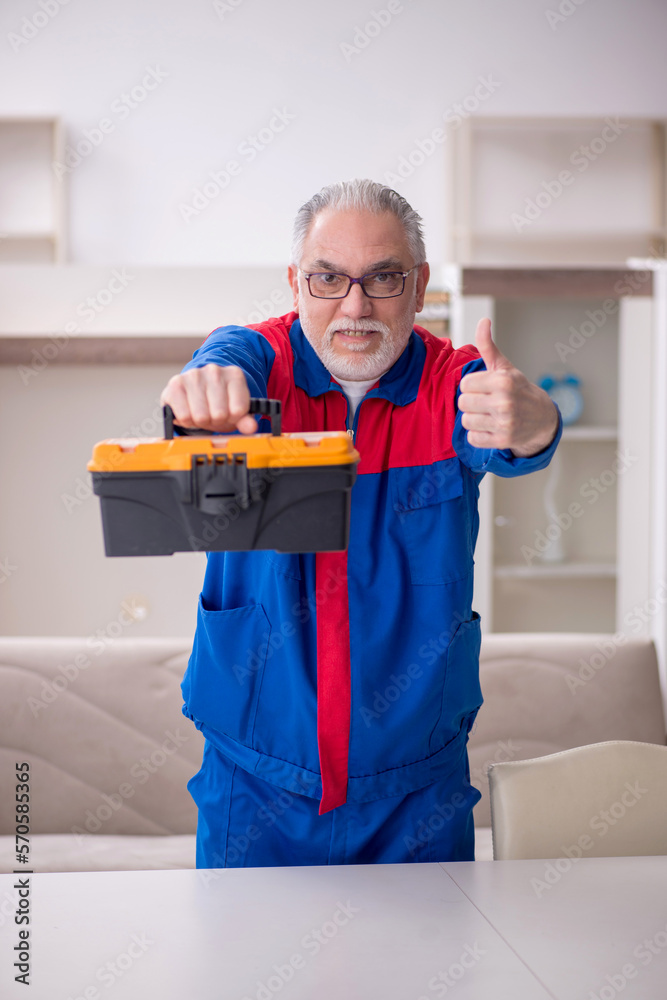 Old male carpenter holding toolbox Old male carpenter holding toolbox