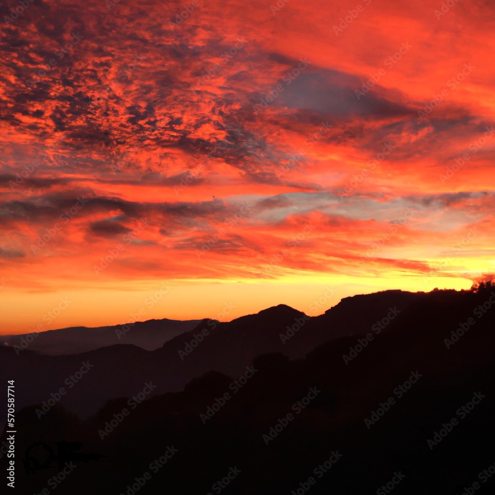 A red-orange sunset over a mountainous landscape