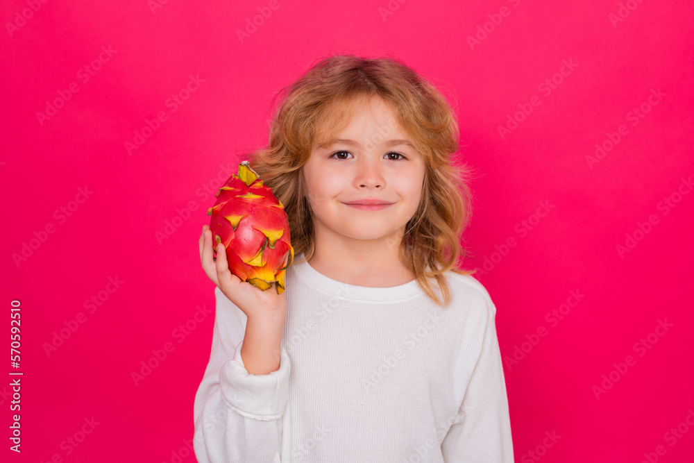 Vitamin and healthy fruits for kids. Kid hold dragon fruit in studio. Studio portrait of cute child with dragon fruit isolated on red background, copy space. Vitamin and healthy fruits for kids. Kid hold dragon fruit in studio. Studio portrait of cute child with dragon fruit isolated on red background, copy space.