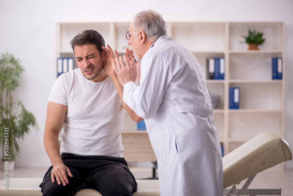Young male doctor visiting old doctor otolaryngologist Young male doctor visiting old doctor otolaryngologist