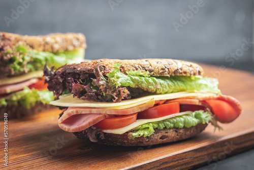 Sandwich with a ham, cheese, tomato, salad lettuce on a wooden board. Lunch concept with copy-space