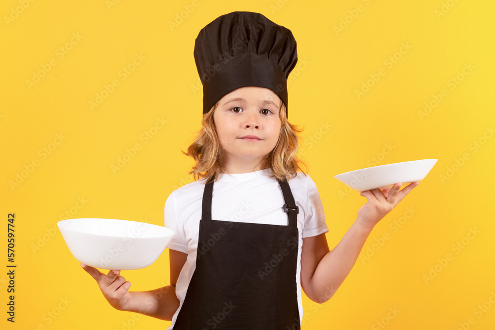 Little cook with cooking plate. Child in cook uniform. Chef kid isolated on yellow background. Cute child to be a chef. Child dressed as a chef hat. Little cook with cooking plate. Child in cook uniform. Chef kid isolated on yellow background. Cute child to be a chef. Child dressed as a chef hat.