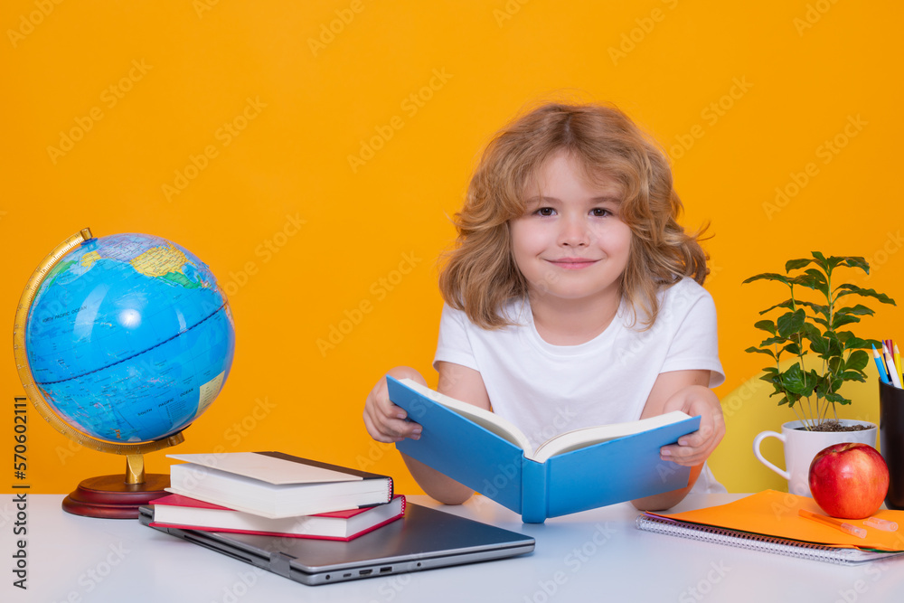 School child reading book. Back to school. Funny little boy from elementary school with book. Portrait of school boy isolated on yellow studio background. Education.