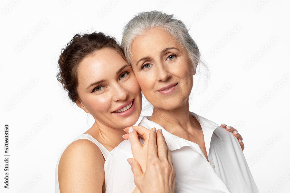 Young beautiful woman and her mother looking happily into the frame together Young beautiful woman and her mother looking happily into the frame together