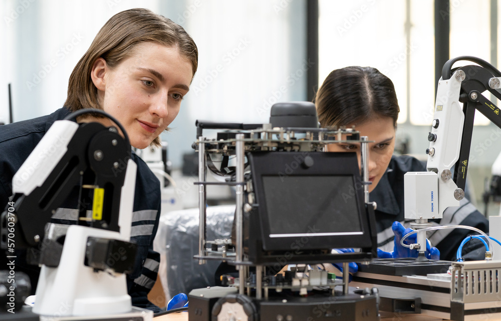 Computer science development engineer working on robotic arm connection and control at electronic futuristic technology center. Modern women training in industry 4.0 automated engineering workshop