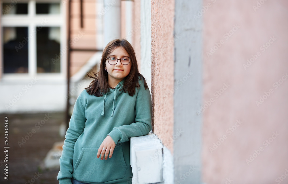 Portrait of a teen girl in glasses leaning on a building outdoors. Portrait of a teen girl in glasses leaning on a building outdoors.