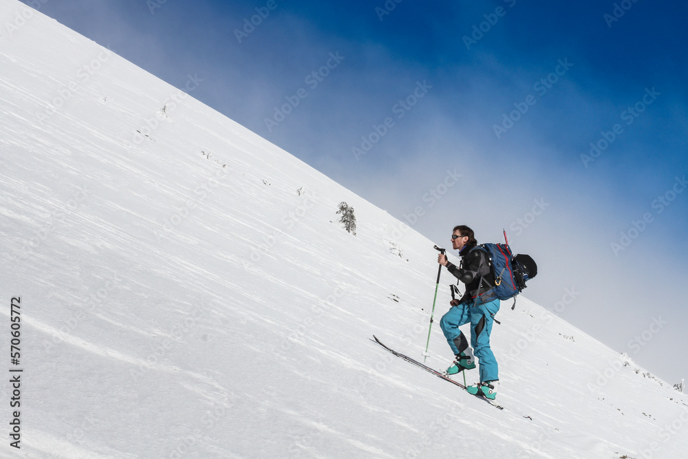 A skier ski tourist climbs a snowy slope