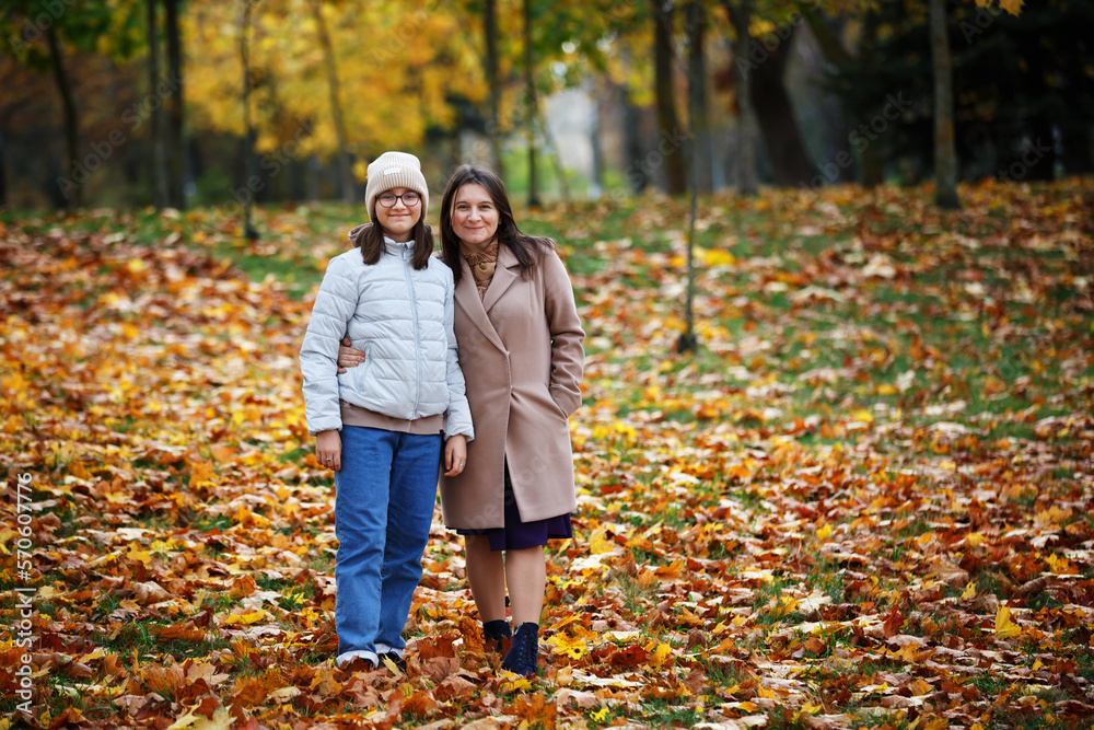 Mom and daughter in the autumn park. Woman and teen girl outdoors. Mom and daughter in the autumn park. Woman and teen girl outdoors.