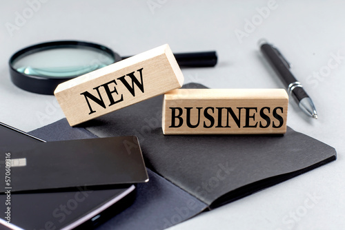 NEW BUSINESS text on wooden block on black notebook , business concept