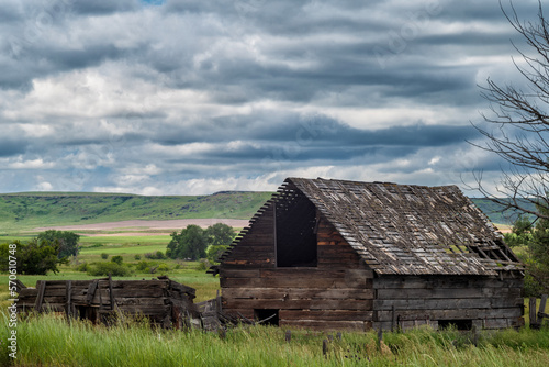 An abandoned wood farm house stands in the grasslands of Pryor, Montana a during stormy afternoon. photo