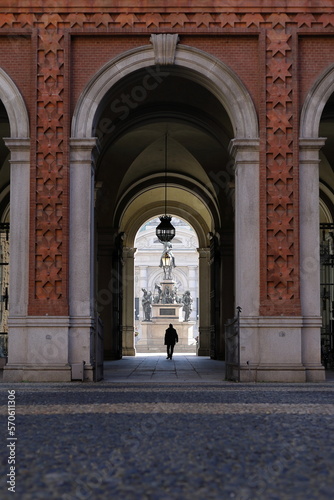 Un signore che passa sotto un arco di palazzo Carignano a Torino
