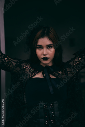 a goth Asian woman dresses up with black make up and wears black clothes like a scary woman at the funeral