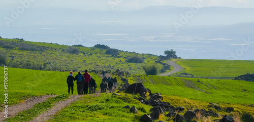 umm qais - irbid, jordan 06- Feb- 2023 - group of travelers walking a hiking trail between green fields and blue sky