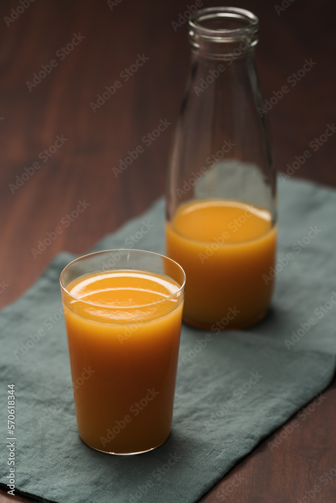 Fresh organic orange juice in tumbler glass on wood table Fresh organic orange juice in tumbler glass on wood table