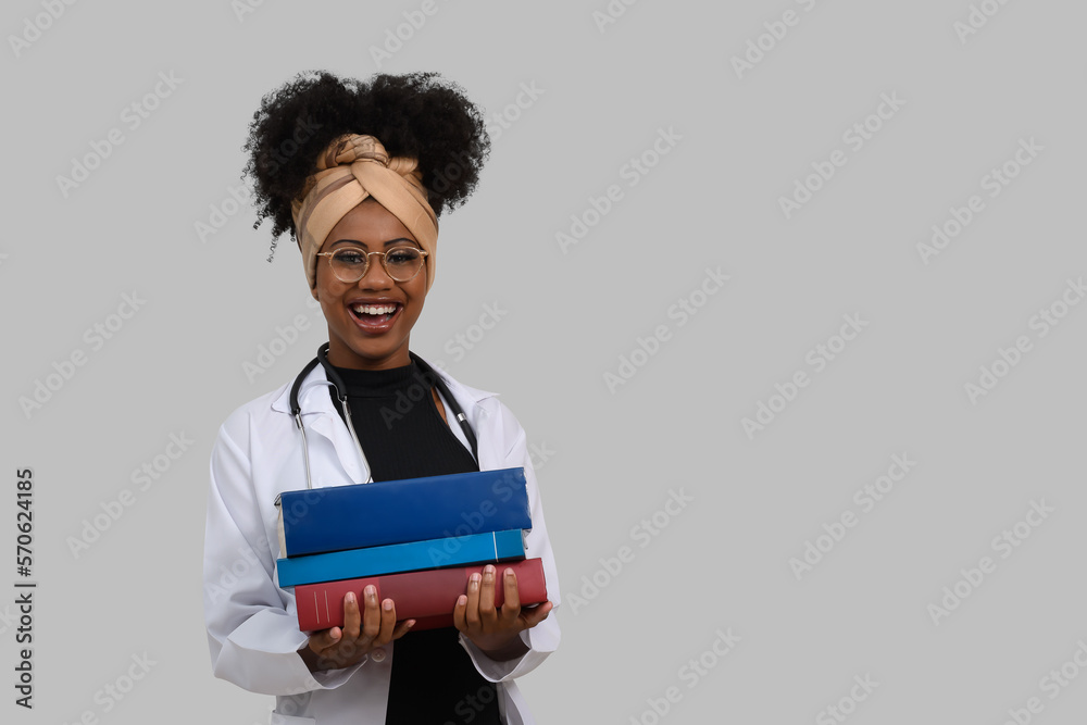 young woman medical student with textbooks looks at camera and smiles. on gray background young woman medical student with textbooks looks at camera and smiles. on gray background