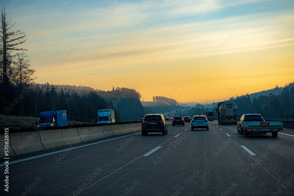 Sonnenaufgang über der winterlichen Autobahn BAB 8, Stuttgart - München, mit Pkw und Lkw, Winterdienst und trockenen, salzbelegtem Asphalt, Fahrtsreifen