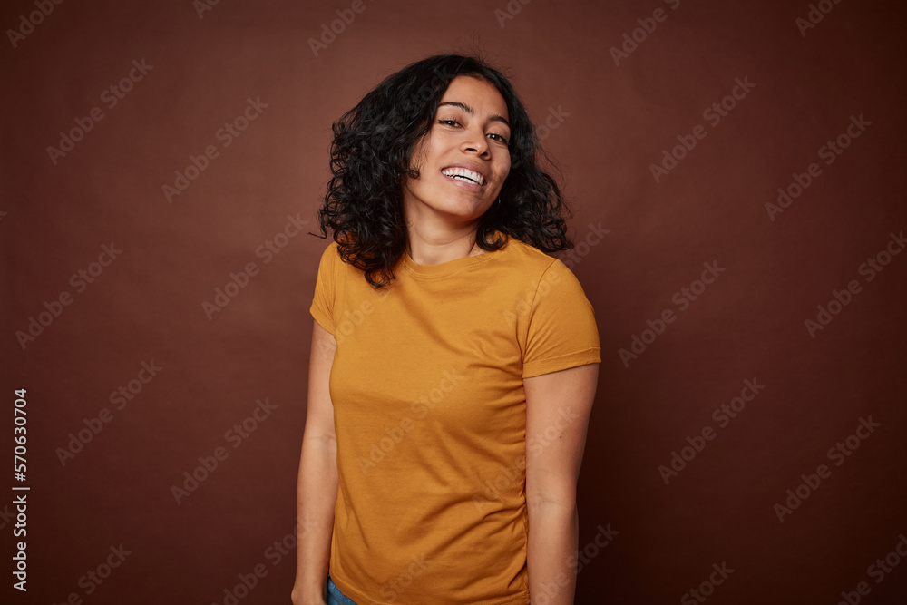 Young colombian curly hair woman isolated on brown background laughs and closes eyes, feels relaxed and happy. Young colombian curly hair woman isolated on brown background laughs and closes eyes, feels relaxed and happy.