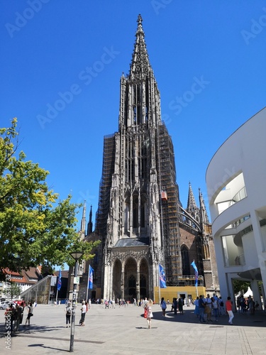 Ulmer Münster im Sommer bei blauem Himmel mit Stadthaus und Passanten