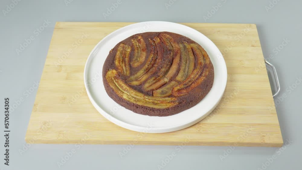 A man transfers a prepared chocolate cake with bananas to another plate. High quality 4k footage A man transfers a prepared chocolate cake with bananas to another plate. High quality 4k footage