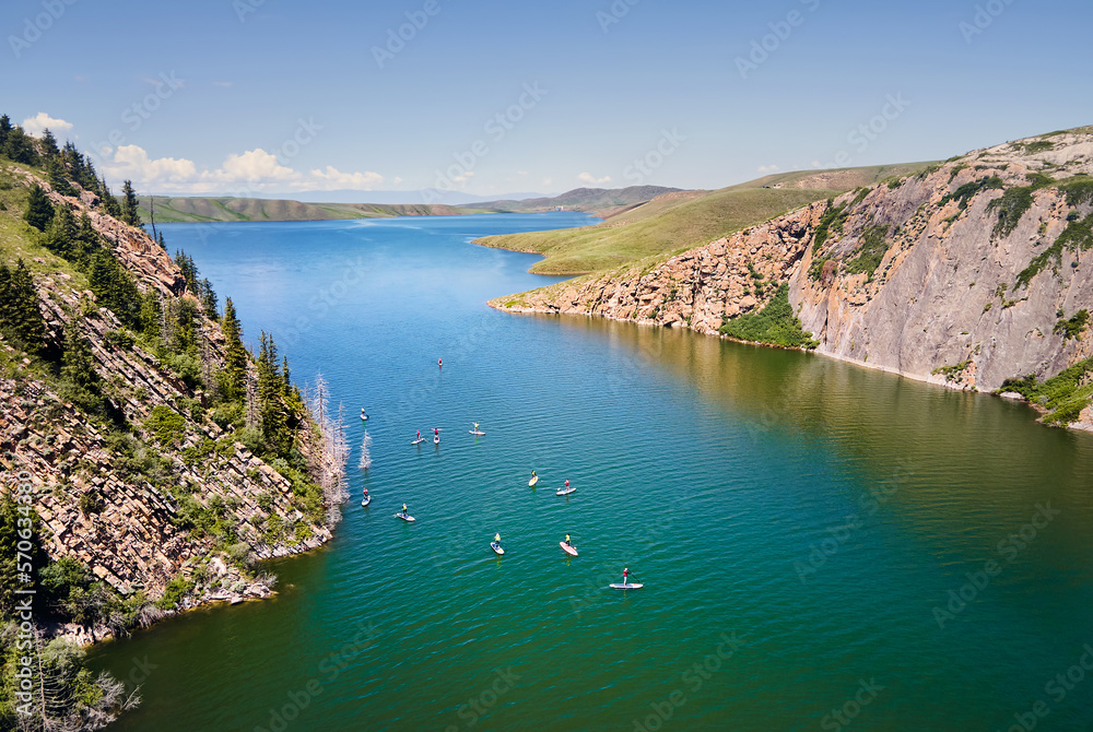 Group of people ride on SUP board in the mountain lake