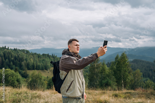 A male tourist with a smartphone in his hands is looking for a mobile network in the mountains with serious faces during a hike.