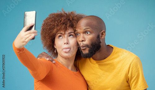 Couple, hug and funny faces selfie on blue background, isolated mockup or wall mock up for social media. Comic, goofy and silly black man and woman on photography tech for interracial profile picture
