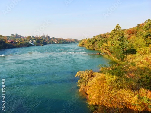 Defocus blurred landscape blue river water surface texture with forestry. Trendy abstract nature background. Water waves in sunlight with copy space. Blue watercolor shining