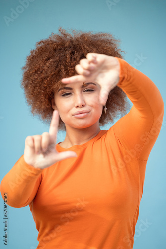 Hands, frame and portrait of black woman on blue background for profile picture. Face, female and finger framing for perspective, selfie and vision of aesthetic focus, idea and photography in studio