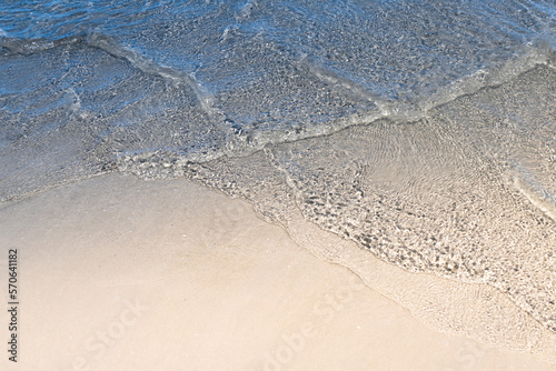 Ocean wave on tropical beach with golden sand and ripple of water splash from emerald blue-green sea water during summer vacation. 