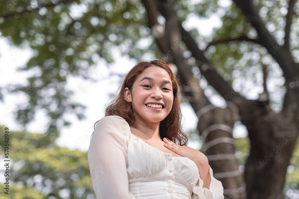 A low-angle shot of a Southeast Asian young lady with a delighted facial expression. A low-angle shot of a Southeast Asian young lady with a delighted facial expression.