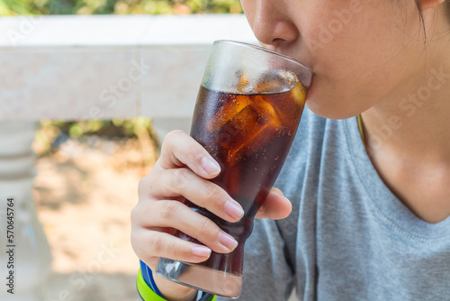 Teenager drinking a glass of cold fizzy cola drink