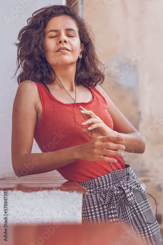 Mulher morena com cabelos cacheados em transição capilar ouvindo e curtindo música. Brunette woman with curly hair in hair transitioning listening and enjoying music.