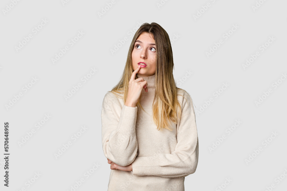 Young blonde posing for a portrait isolated, exuding natural beauty and radiance looking sideways with doubtful and skeptical expression. Young blonde posing for a portrait isolated, exuding natural beauty and radiance looking sideways with doubtful and skeptical expression.