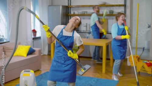 Funny workers of cleaning service cleaning up and dancing. Realtime