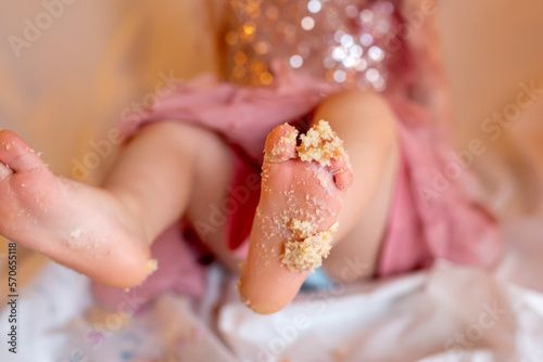 Feet of toddler girl in cake - birthday celebration