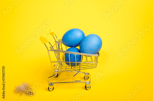 Supermarket trolley with blue easter eggs. Concept of buying