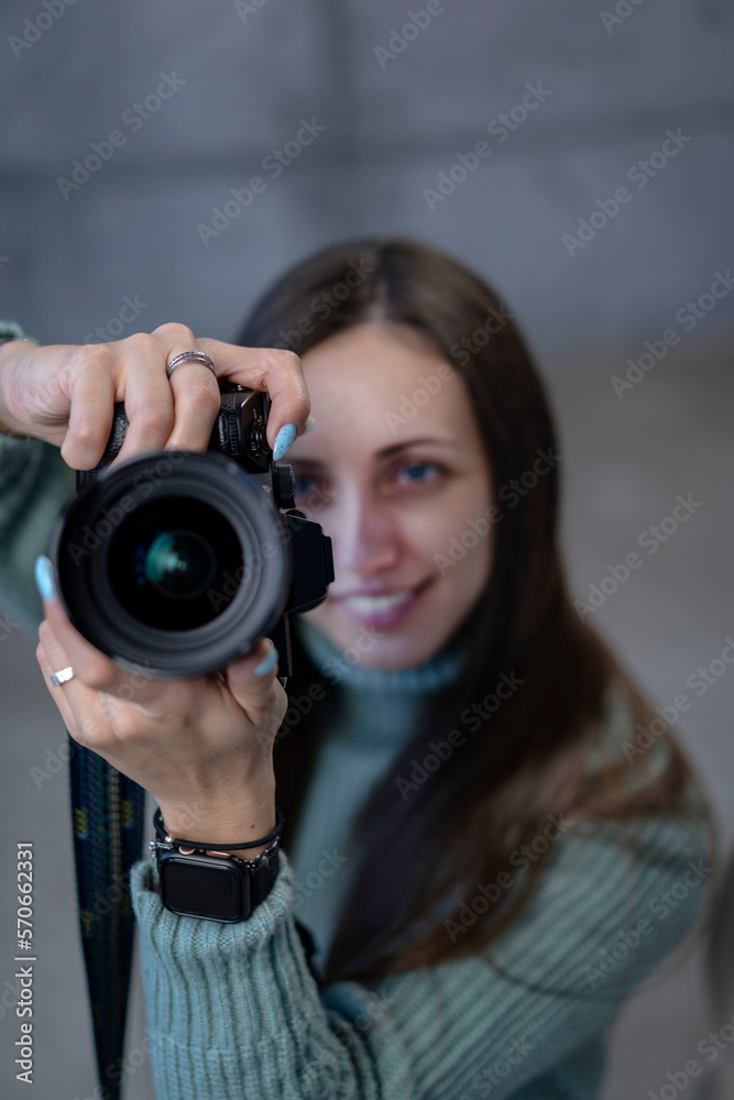 beautiful girl with a modern camera in her hands in a green dress. looking at the camera smiling