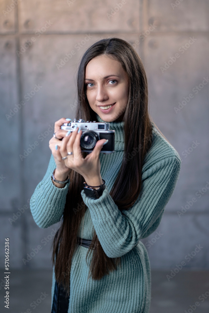 beautiful girl with an old camera in her hands in a green dress. looking at the camera smiling