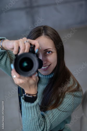 beautiful girl with a modern camera in her hands in a green dress. looking at the camera smiling
