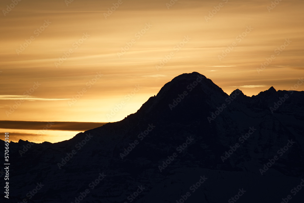 Silhouette of a moutain in switzerland - early morning with strong yellow background