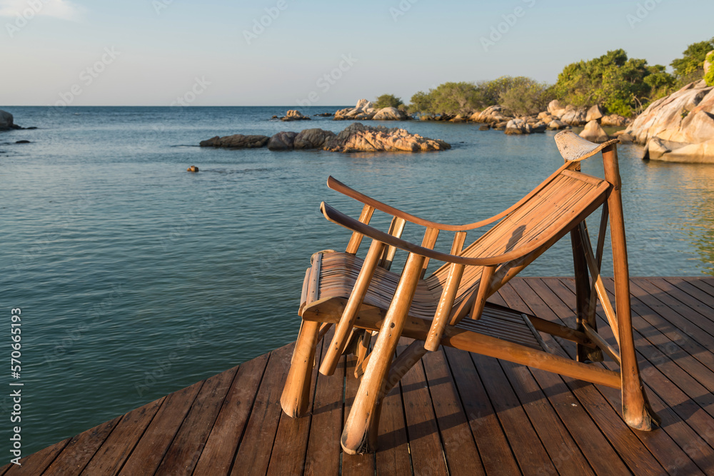 Wooden sunbed or deck chair at resort patio by the sea