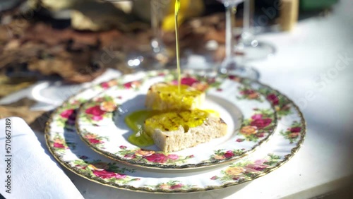 Traditional crusty Italian bruschetta poured with extra virgin olive oil, seasoned with salt and pepper. Tasty grilled bread on plate served in Italian rustic restaurant, fresh olive oil being poured photo