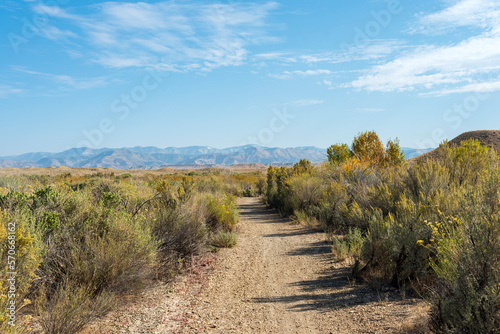 Recreational hiking and biking trail in the high desert in western Colorado, part of Highline Lake State Park with natural vegetation including sage and rabbit brush. 