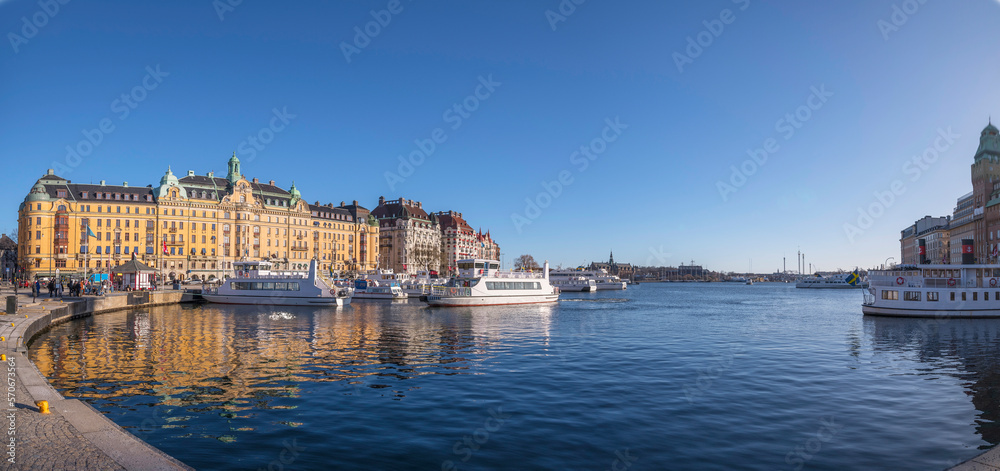 Panorama, pier at the jetty Strandvägen with commuter boats, waterfront hotels, offices and apartment buildings a sunny winter day in Stockholm