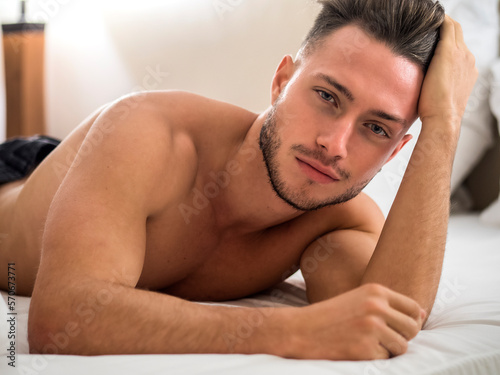 Shirtless sexy male model lying alone on his bed