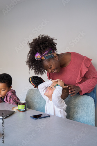 Toddler son playing while his african mother tries to style his hair using an afro curl or twists sponge. photo