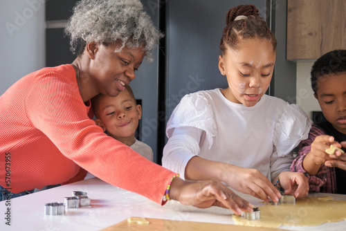 Φωτογραφία African family cutting cookie shapes in a cookie dough in the kitchen
