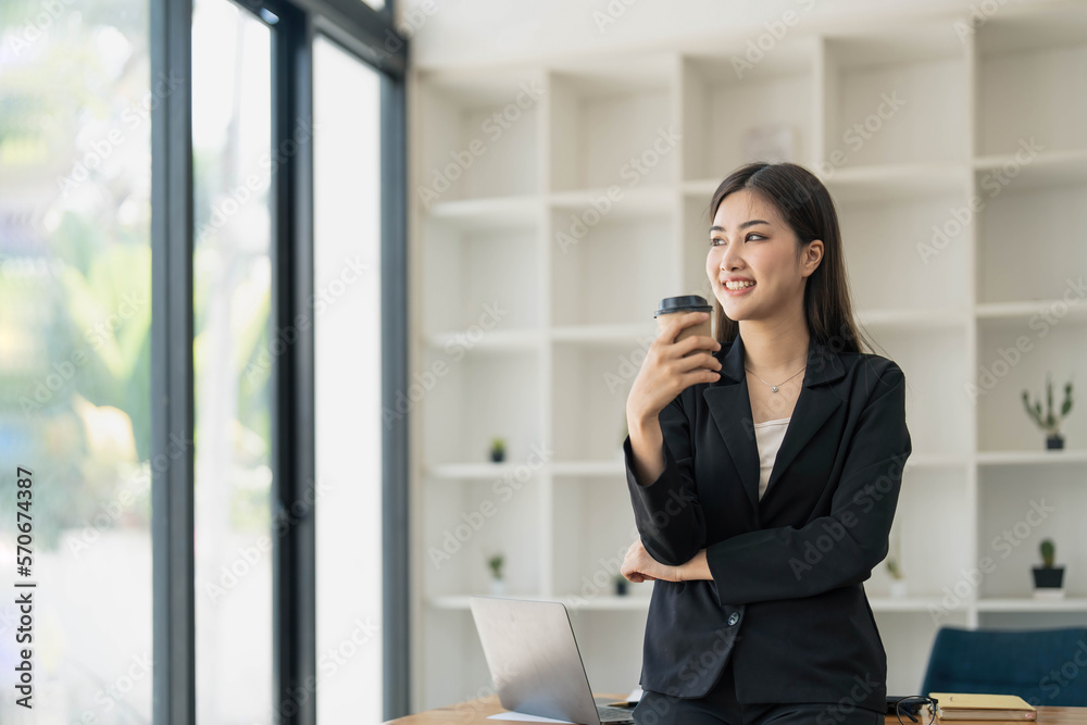 Portrait of young confident woman holding coffee cup, standing at office and looking outside. Successful businesswoman standing in office with copy space. Portrait of young confident woman holding coffee cup, standing at office and looking outside. Successful businesswoman standing in office with copy space.